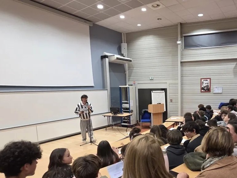 Esope au micro devant une classe, en amphithéâtre, pendant un atelier slam