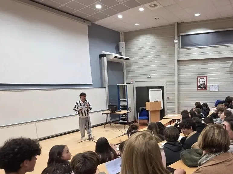 Esope au micro devant une classe, en amphithéâtre, pendant un atelier slam